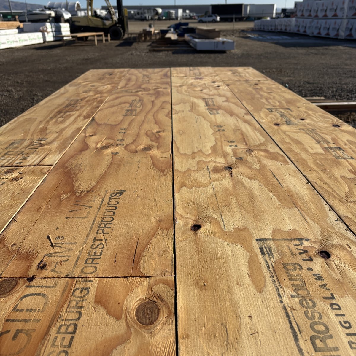Forklift positioned behind stacked 1-3/4 inch by 14 inch LVL beams at Boise lumberyard showing inventory and yard handling context