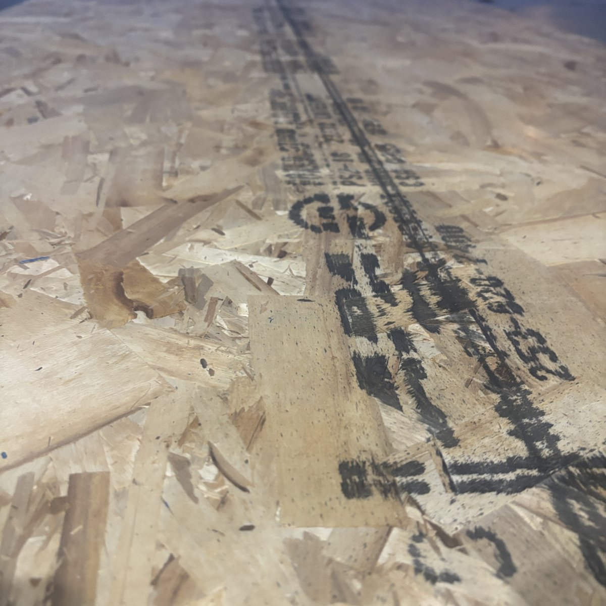 Angled view of OSB strand texture on 23/32 inch tongue-and-groove subfloor sheathing panel